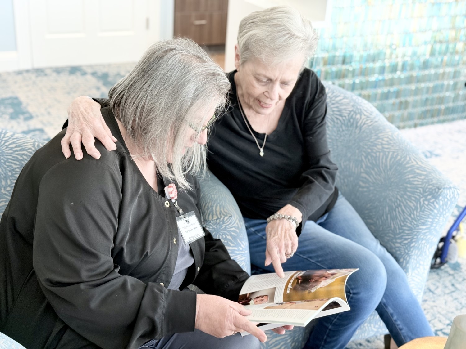 woman and nurse talking, looking at magazine