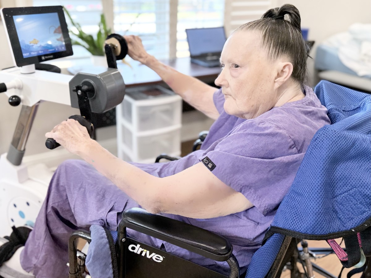 senior woman resident in a wheelchair on therapy bike in physical therapy in nursing home in GreenAcres Place in Bossier City, LA