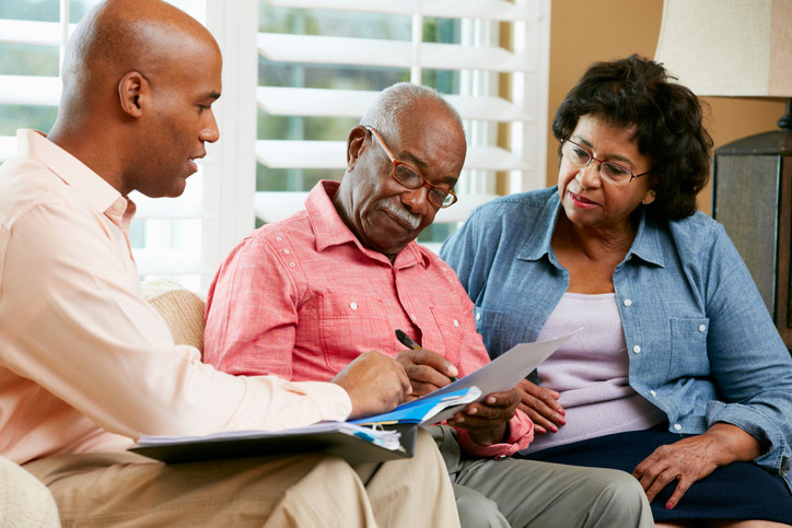 A man and woman sit on a couch with an older man, discussing a care facility in Bossier City, LA