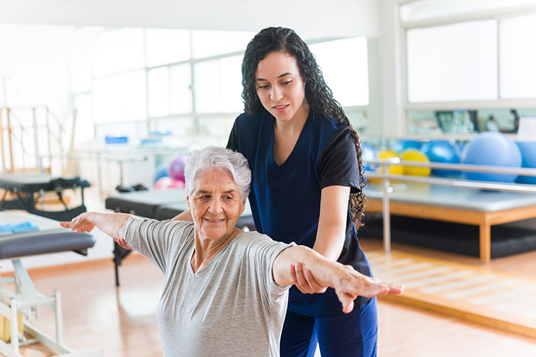 A physical therapist in Bossier City helps a senior woman stretch her arms
