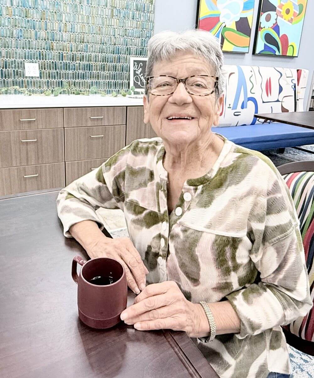 Older woman at a table with a coffee cup, representing Pilgrim Manor in Bossier City, LA