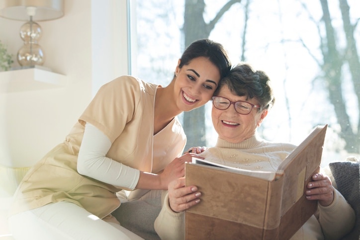 Resident with dementia looking at a family photo album with a nurse